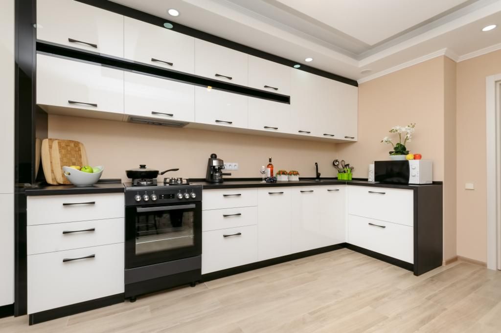 A kitchen with black and white cabinets and a stove.