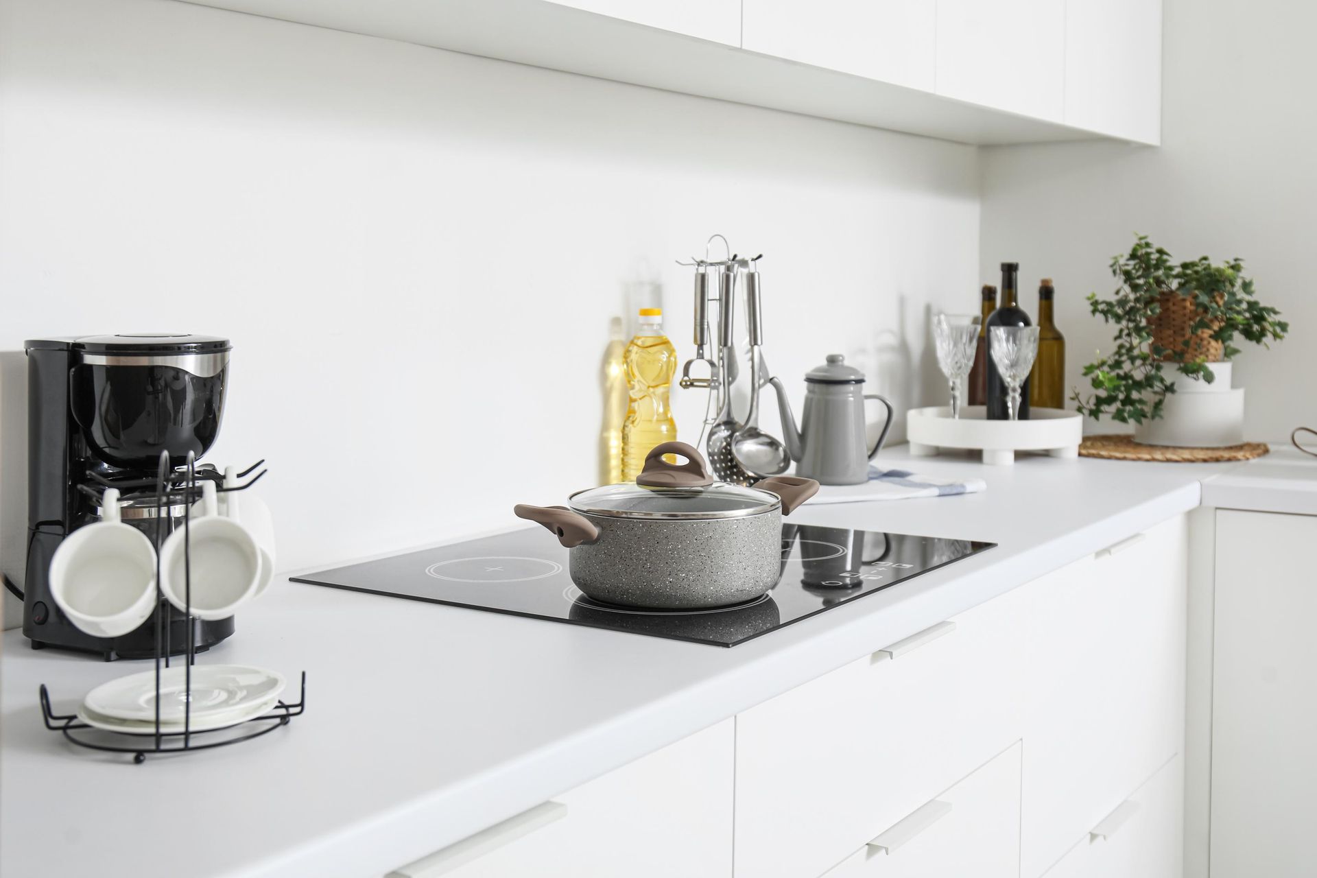 A kitchen with white cabinets and a pot on the stove.