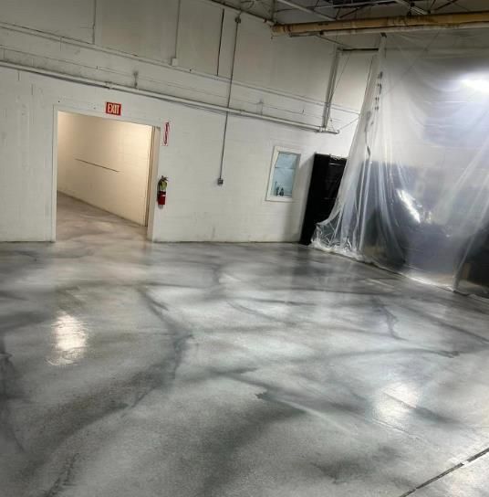 A large empty room with a concrete floor and white walls.