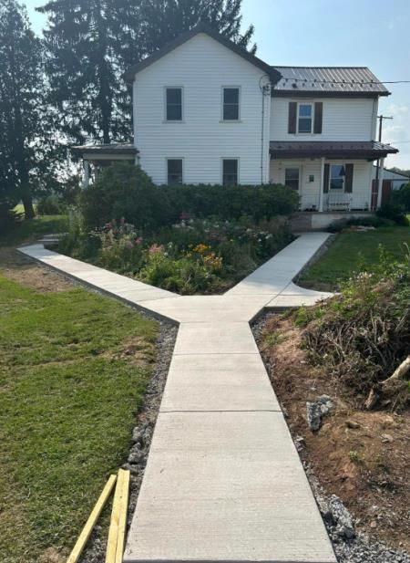 A concrete walkway is being built in front of a white house.