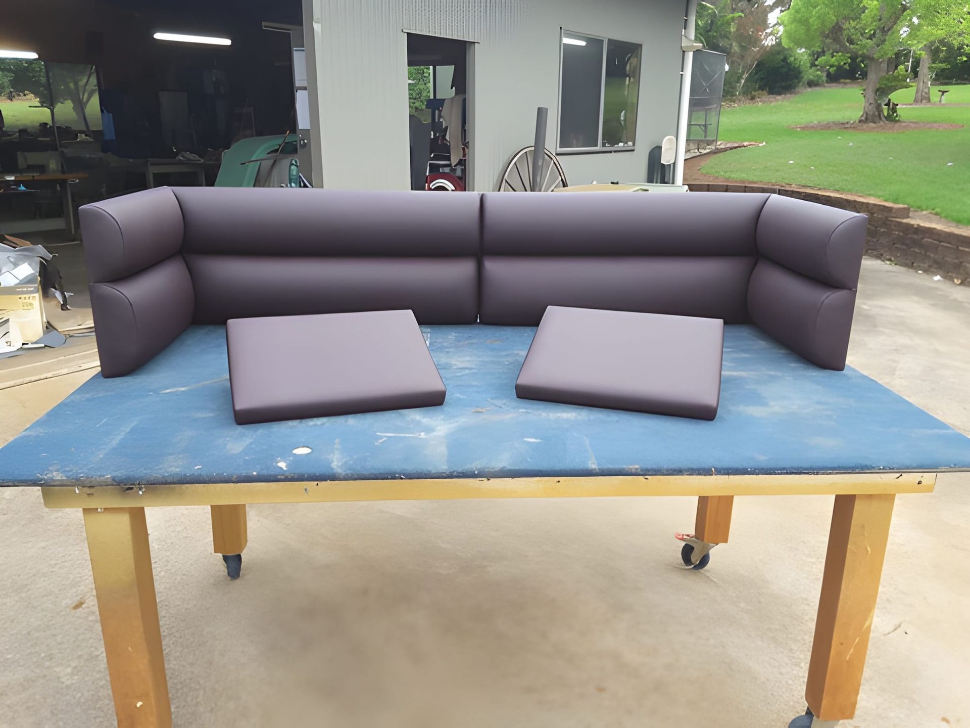 A Dark Brown Sectional Sofa With Two Square Cushions on a Blue Tabletop — Cupitt's Quality Upholstery in Rous, NSW