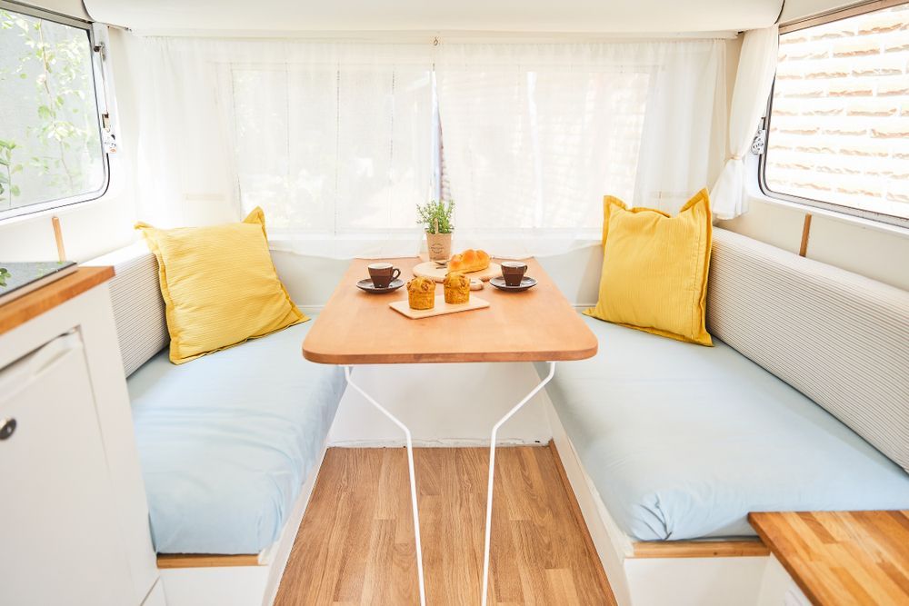 A Cozy Camper Interior With Table, Built-in Seating, and Yellow Pillows — Cupitt's Quality Upholstery in Byron Bay, NSW