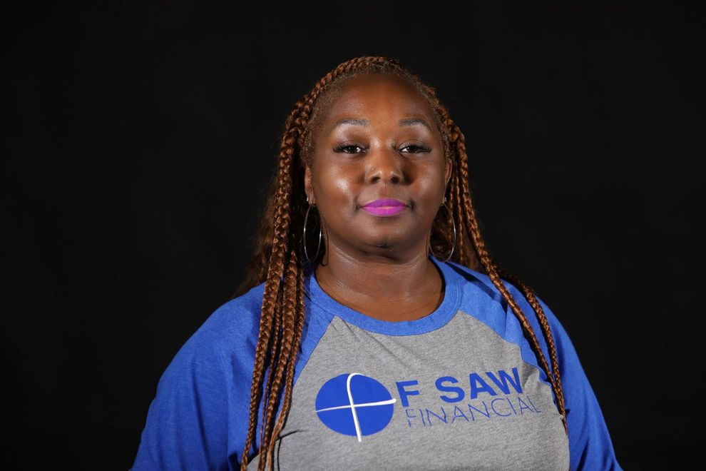 Fola Sawyerr is wearing  a blue and gray t-shirt with the word F Saw Financial on it.