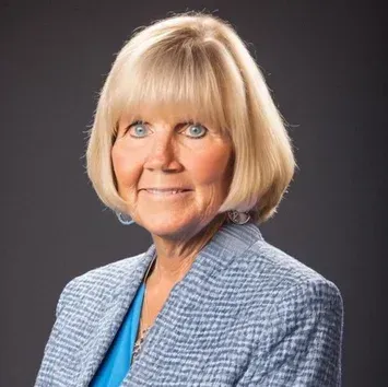 Blonde woman in blue blazer smiles at camera.