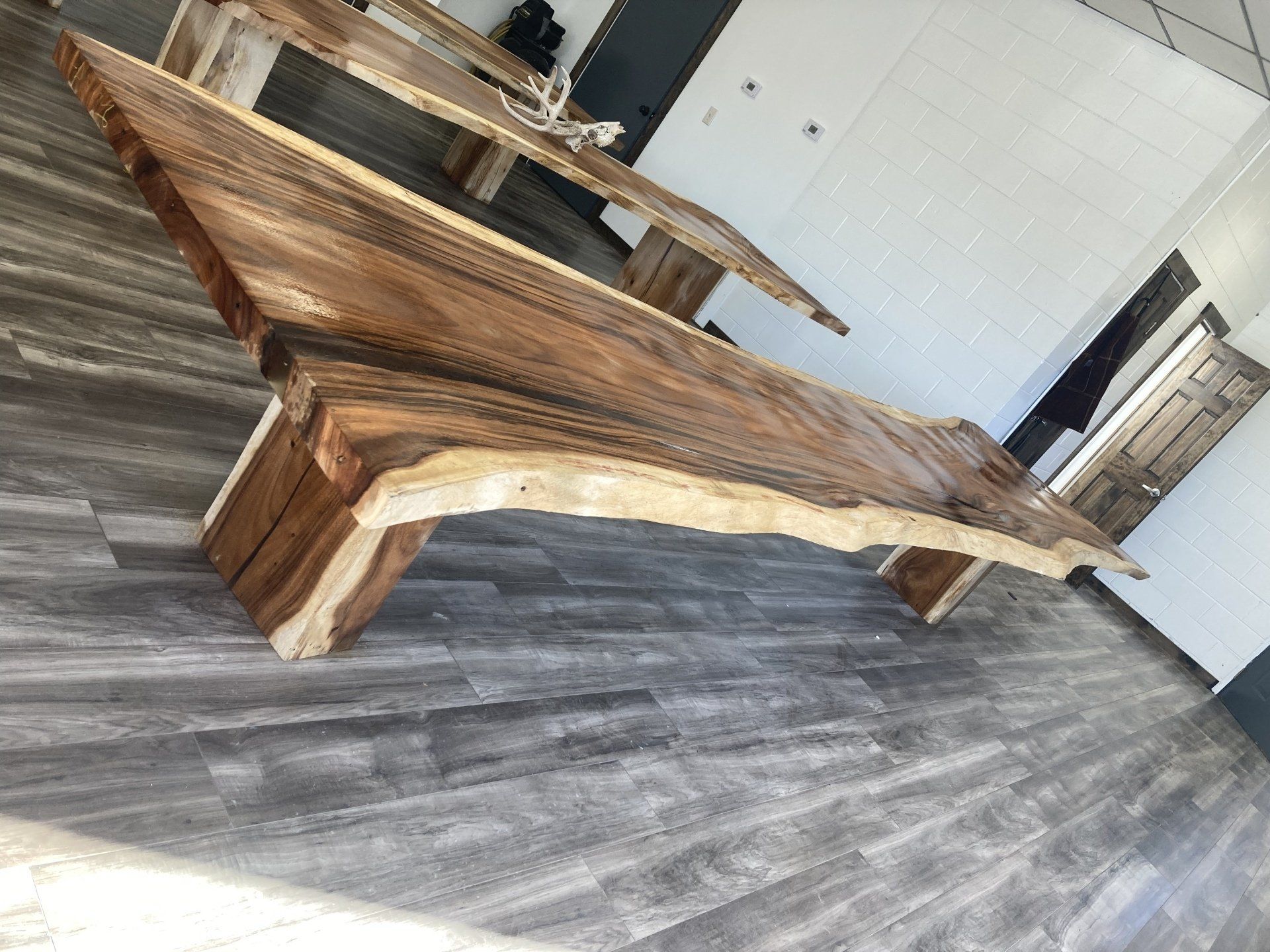 A long wooden table is sitting on a wooden floor in a room.