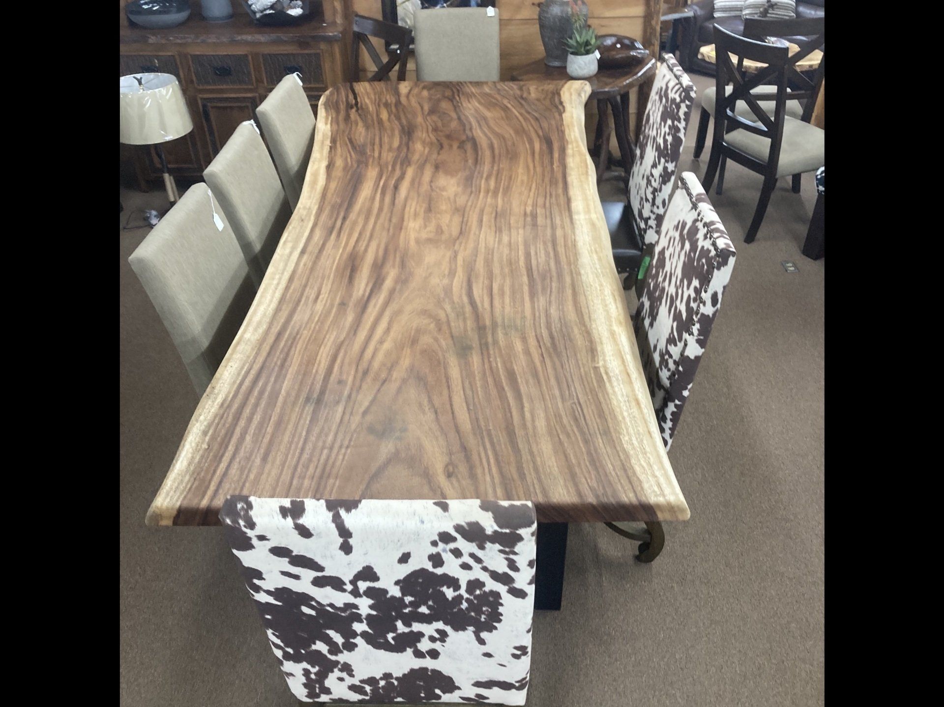 A wooden table with a cow print table cloth on it.