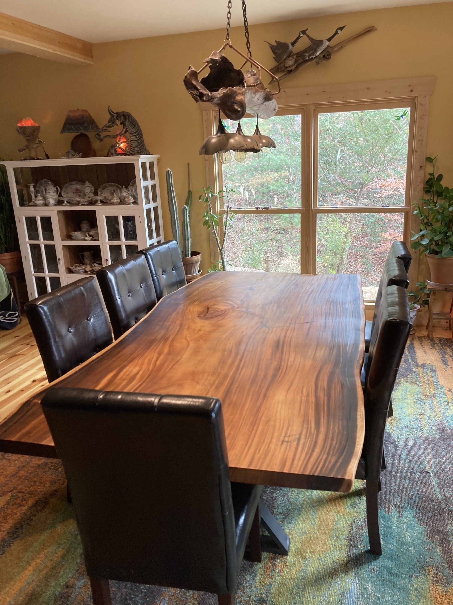 A dining room with a large wooden table and chairs.