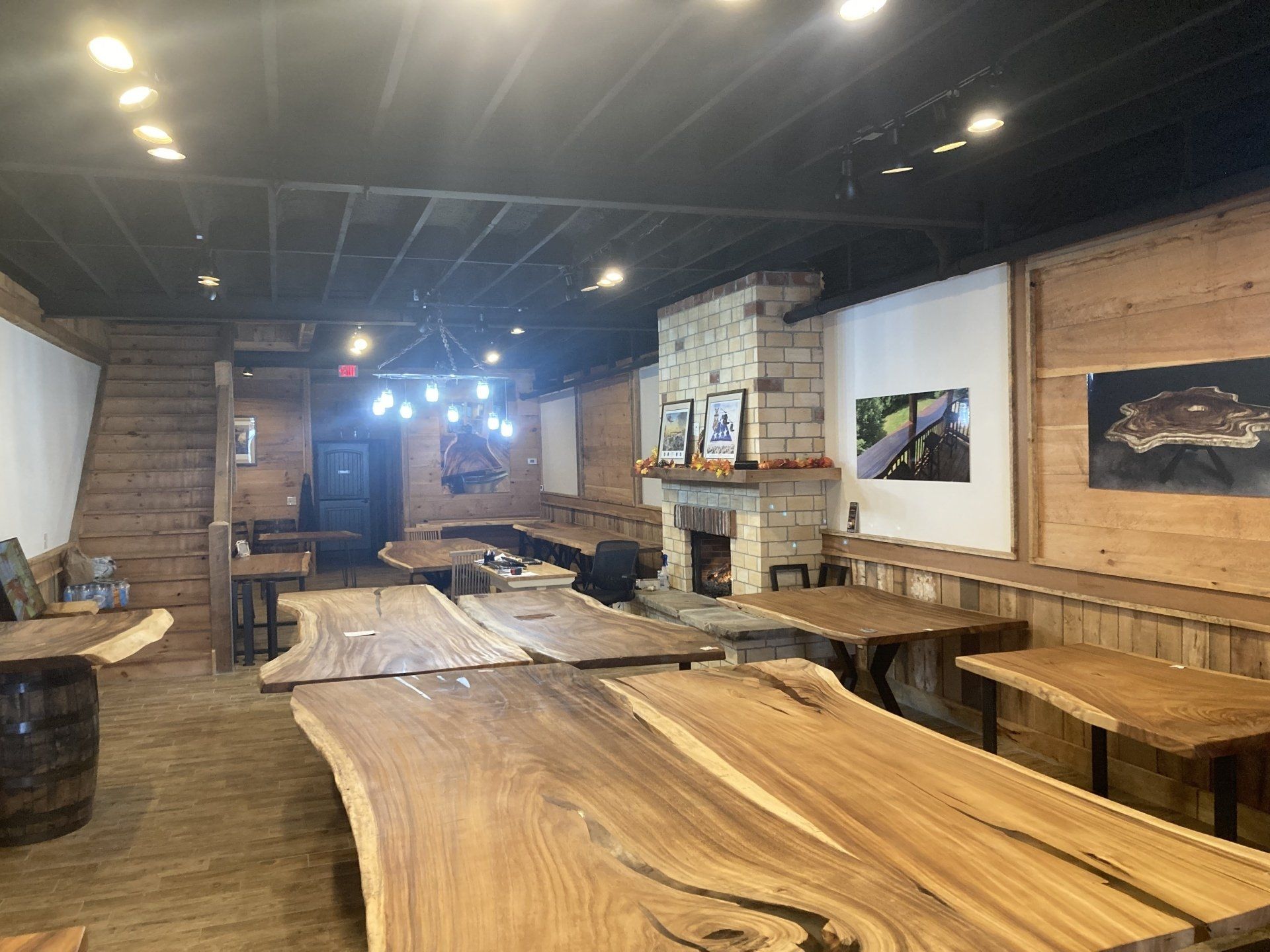 A room with a lot of wooden tables and a fireplace.