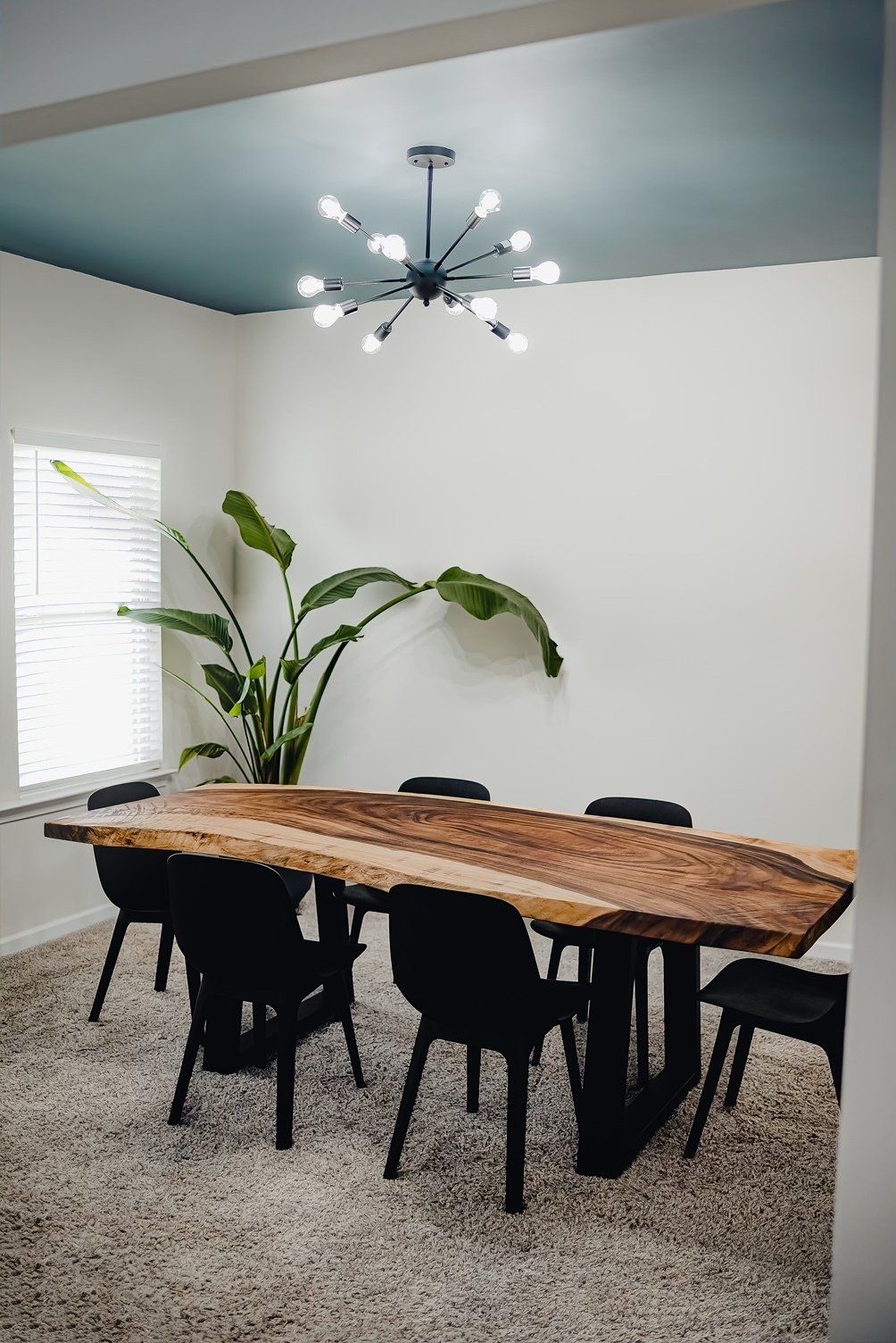 A dining room with a large wooden table and chairs.