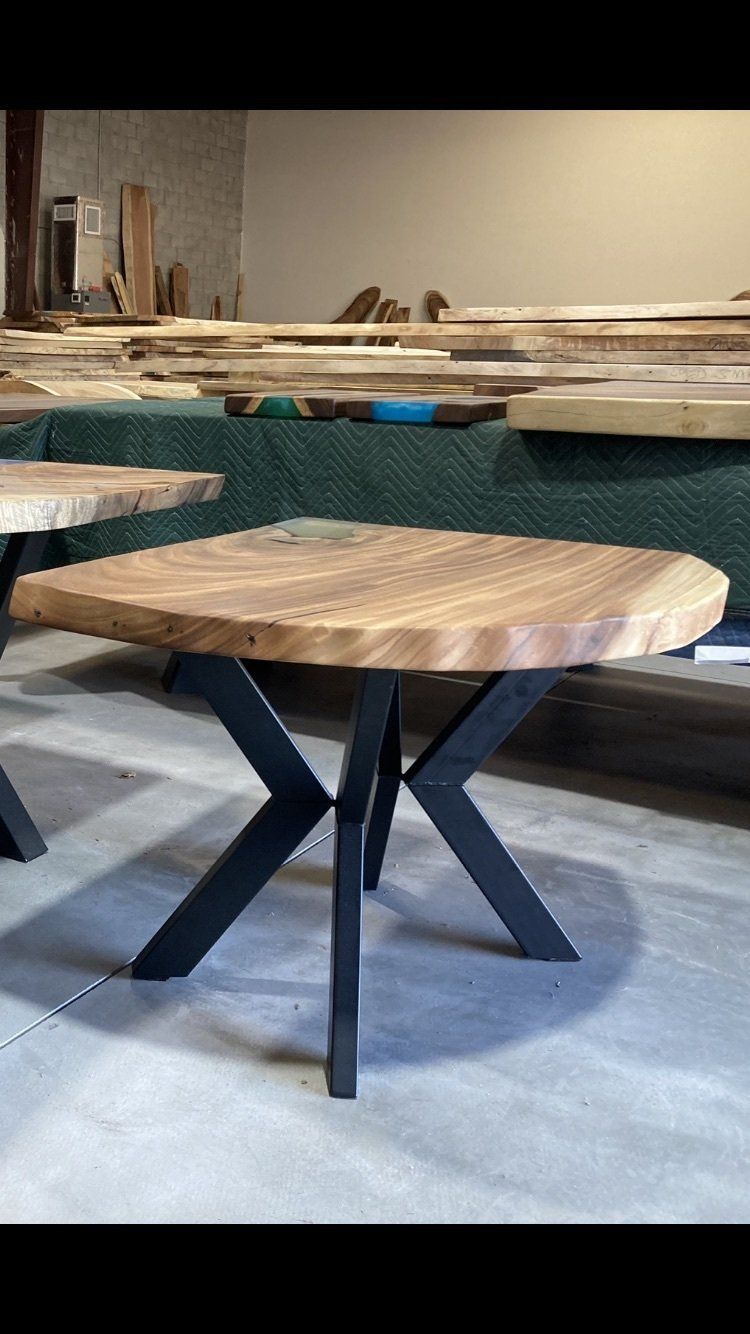A wooden table with a metal base is sitting in a warehouse.