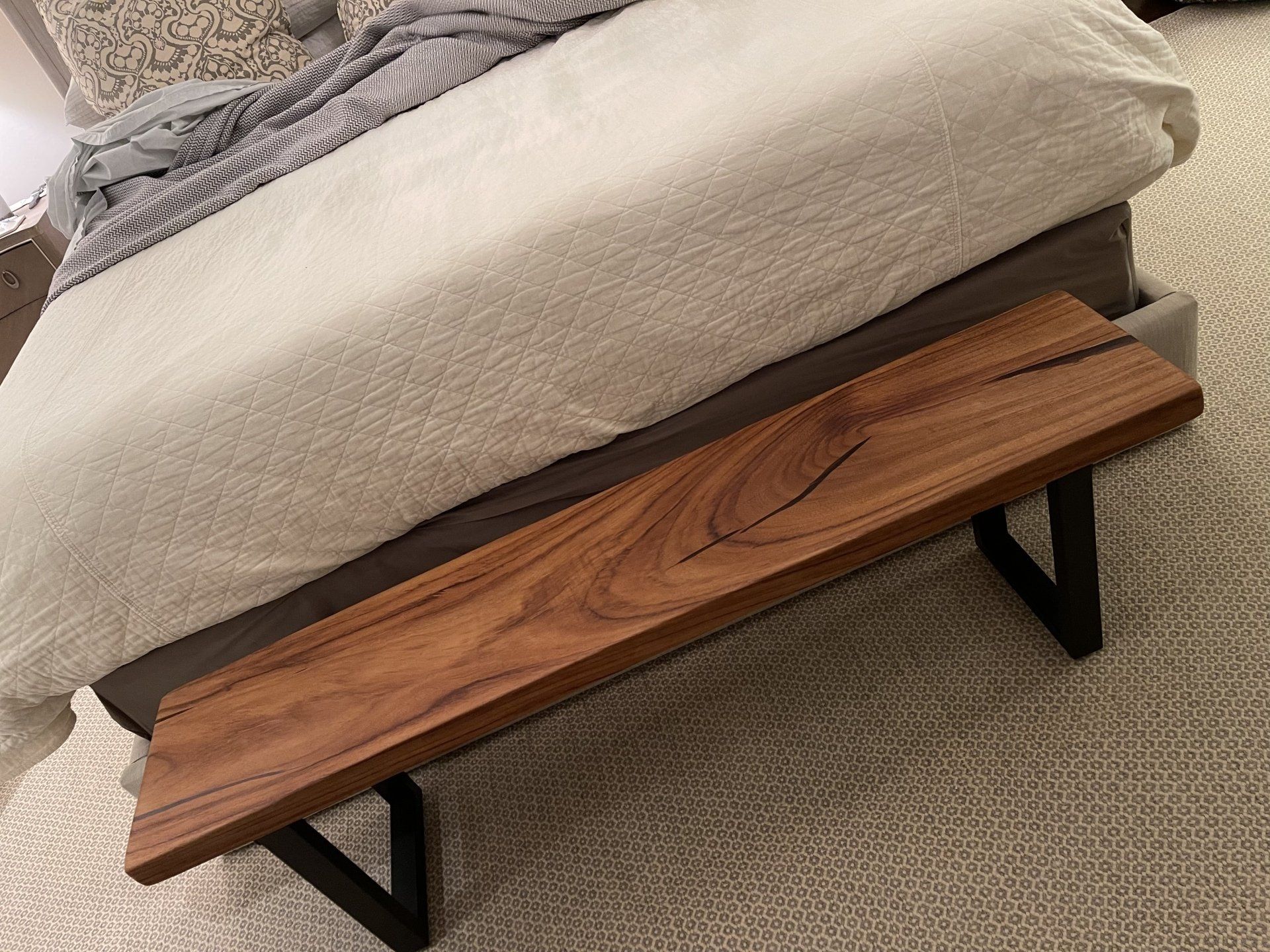 A wooden bench is sitting next to a bed in a bedroom.