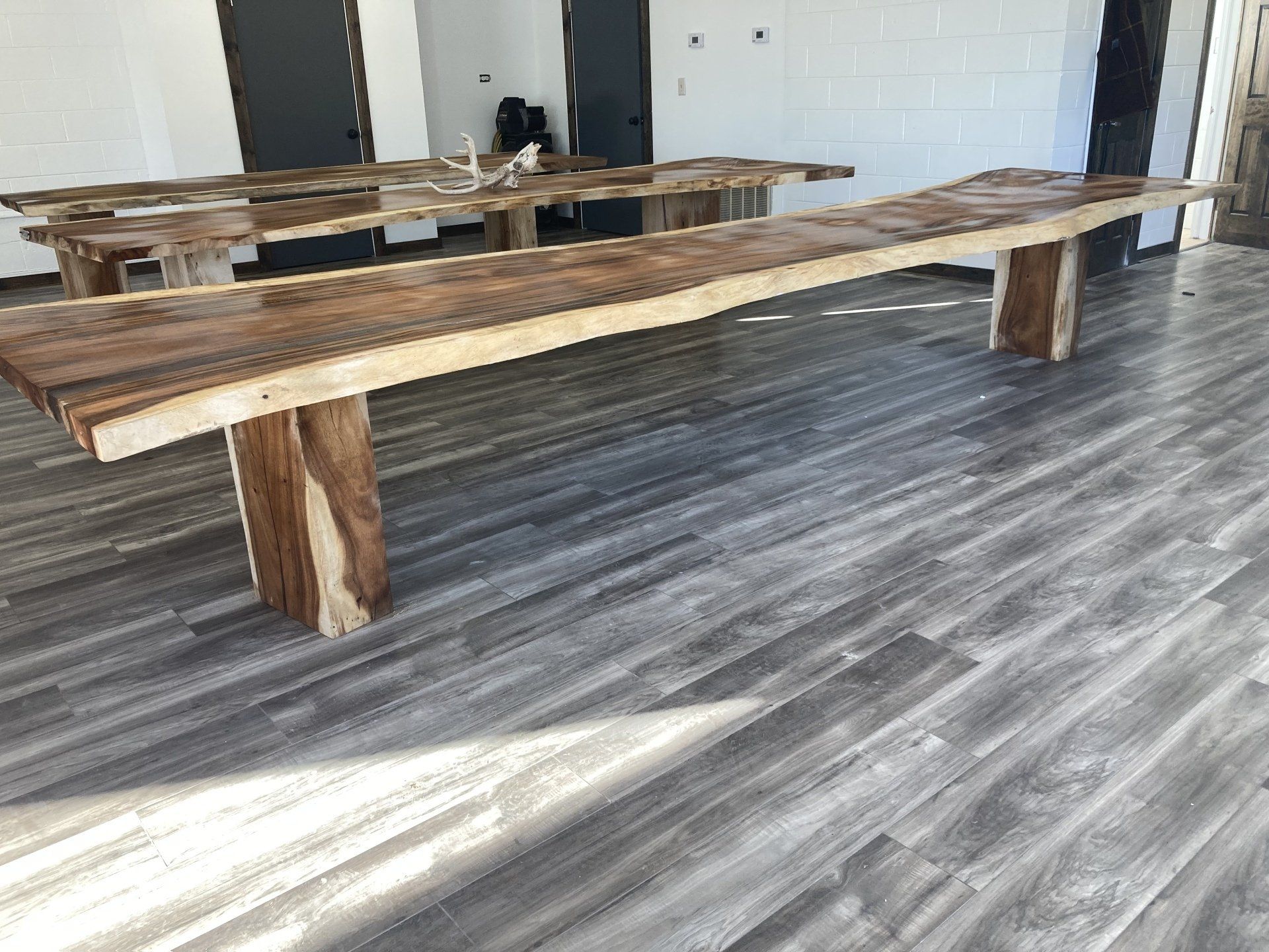 A long wooden table is sitting on a wooden floor in a room.