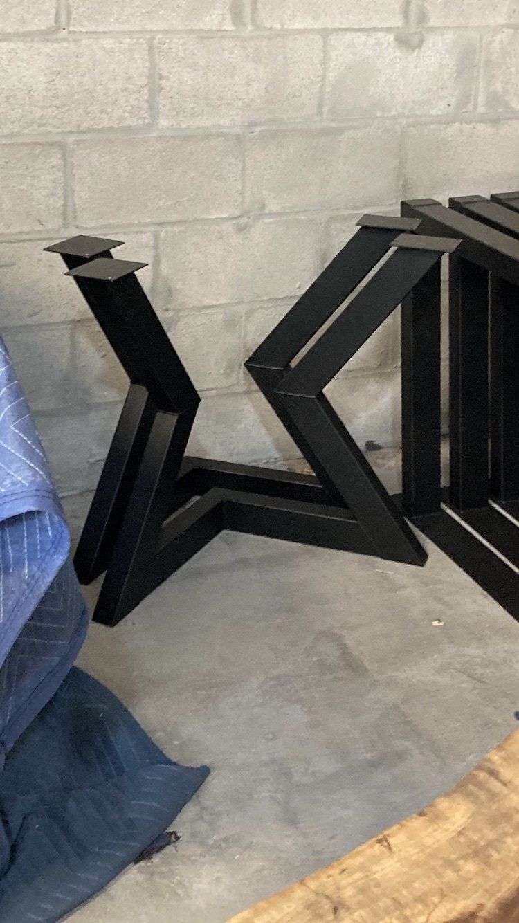 A stack of metal legs sitting on top of a concrete floor next to a brick wall.