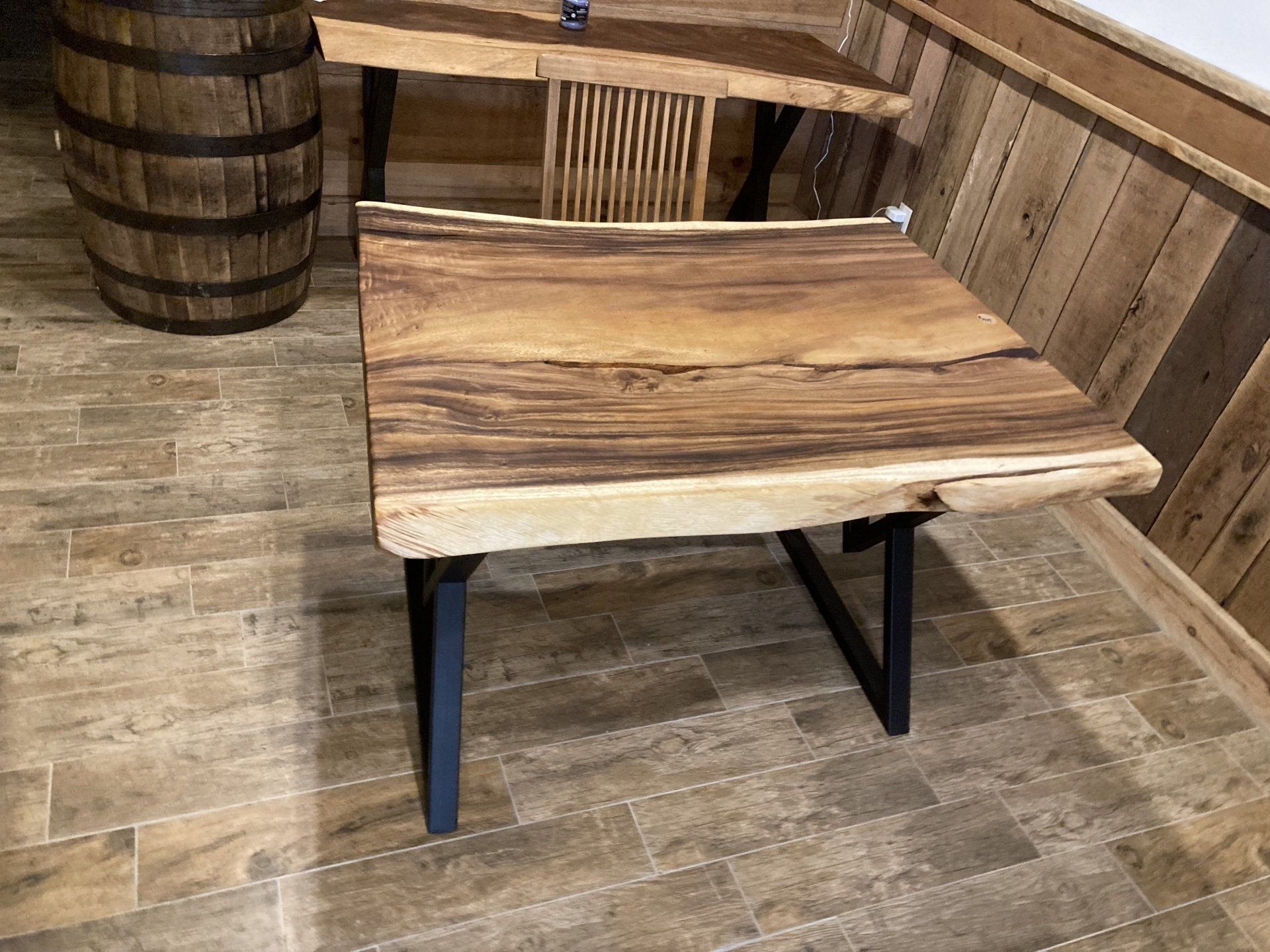 A wooden table is sitting on a tiled floor next to a wooden barrel.