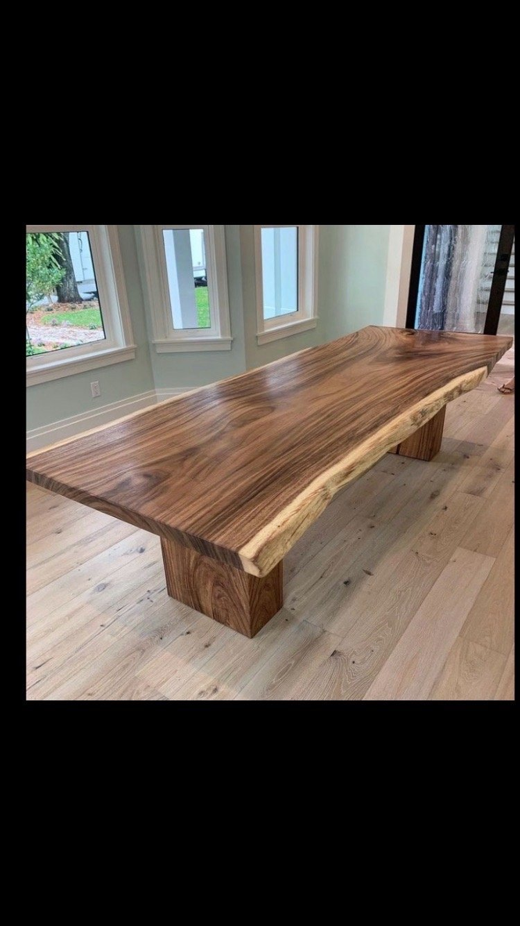 A large wooden table is sitting on a wooden floor in a living room.