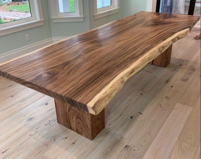 A large wooden table is sitting on a wooden floor in a living room.