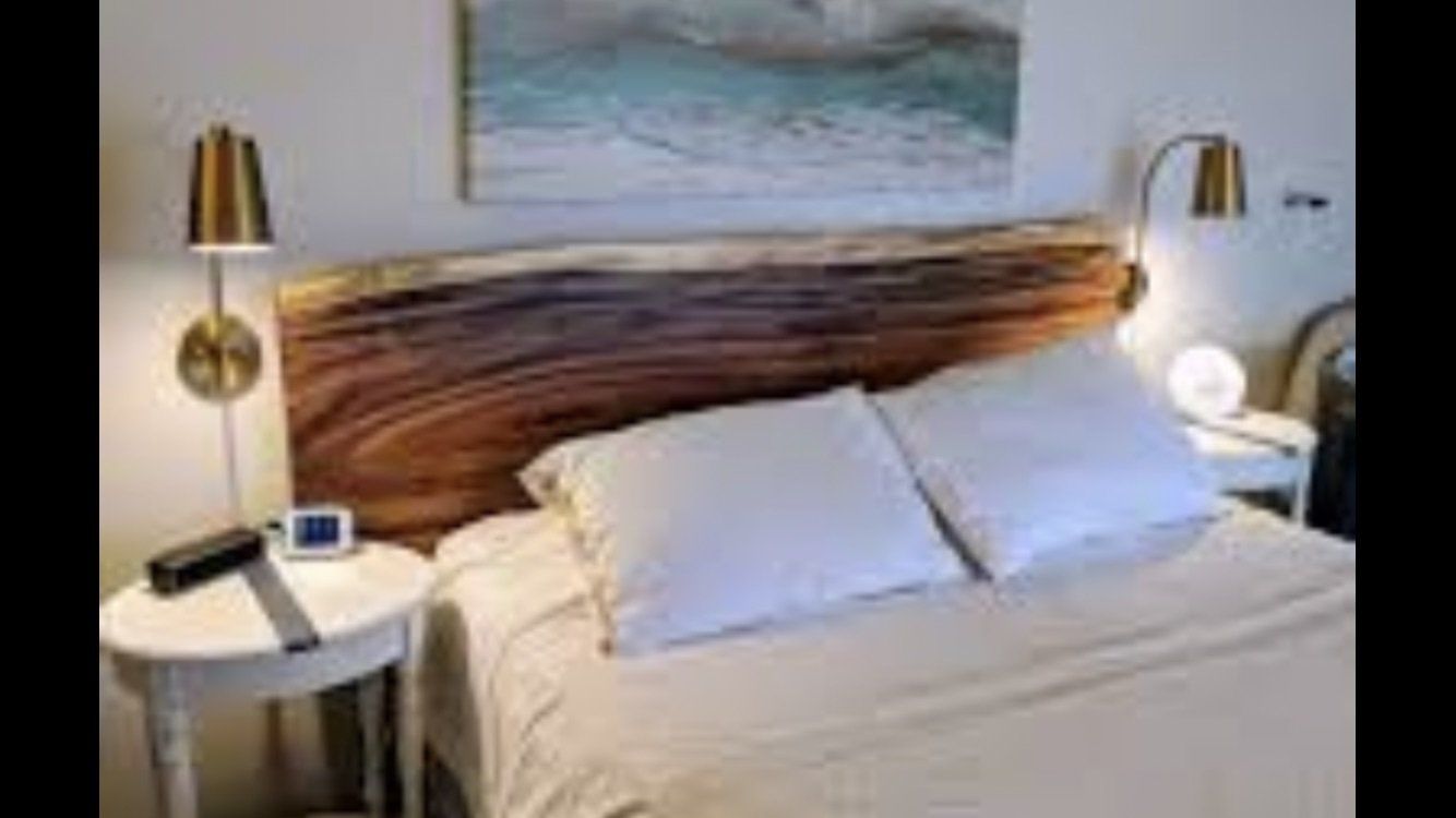 A bedroom with a bed , nightstand , and a wooden headboard.