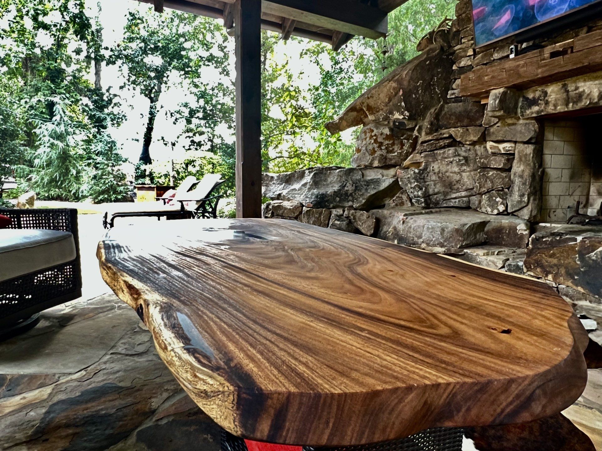 A wooden table is sitting on top of a stone patio next to a fireplace.