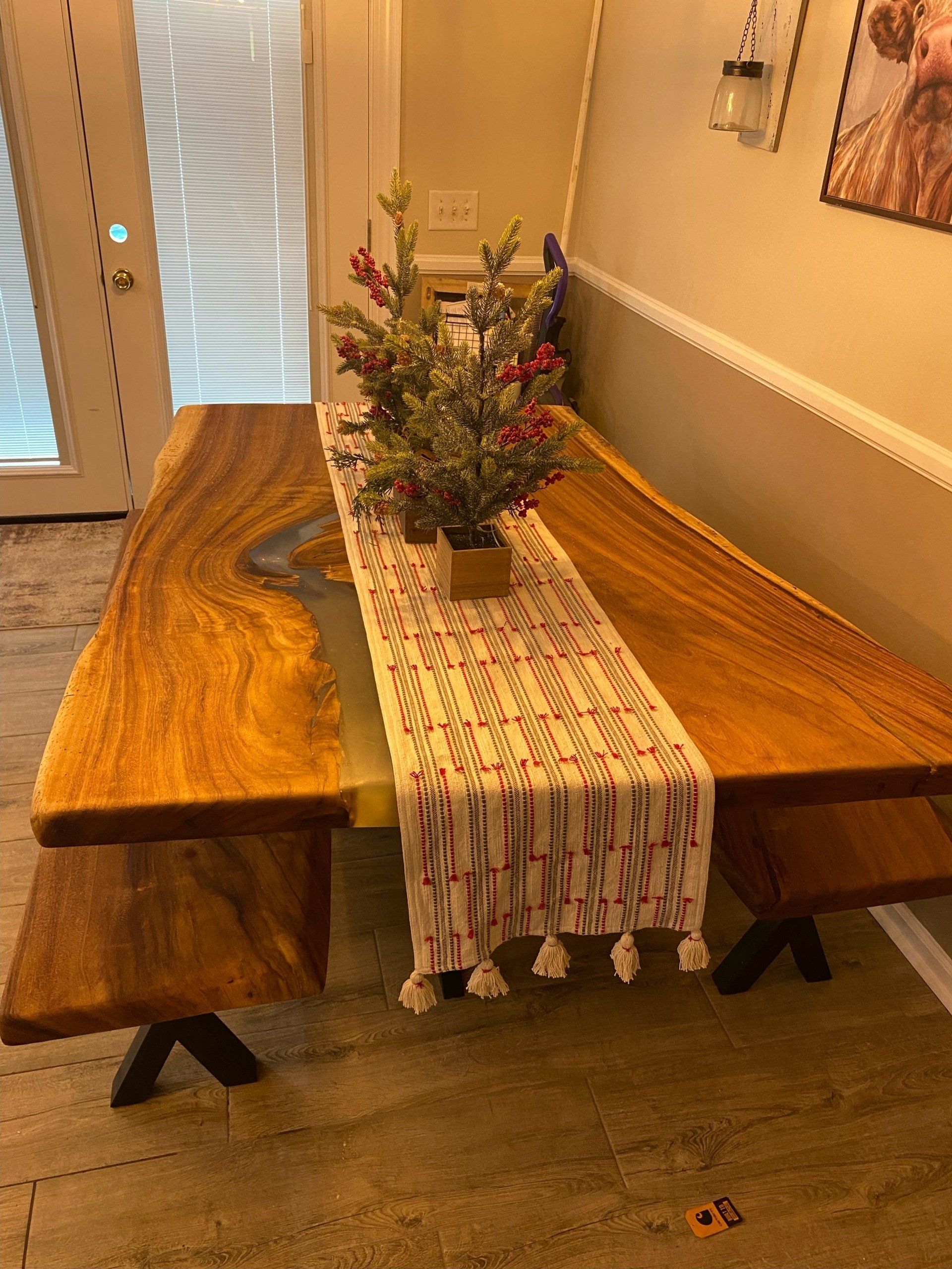 A wooden table with a table runner and a vase of flowers on it.
