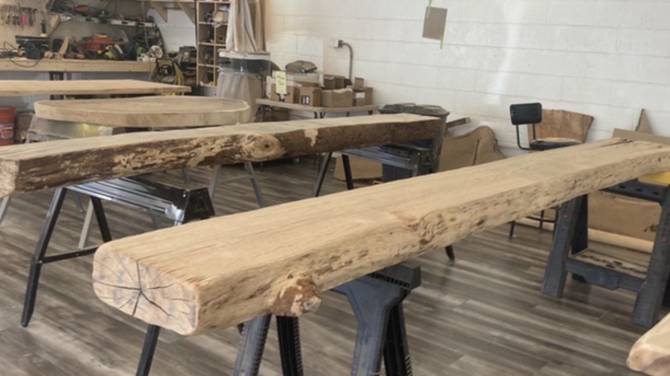 A wooden beam is sitting on top of a wooden table in a workshop.