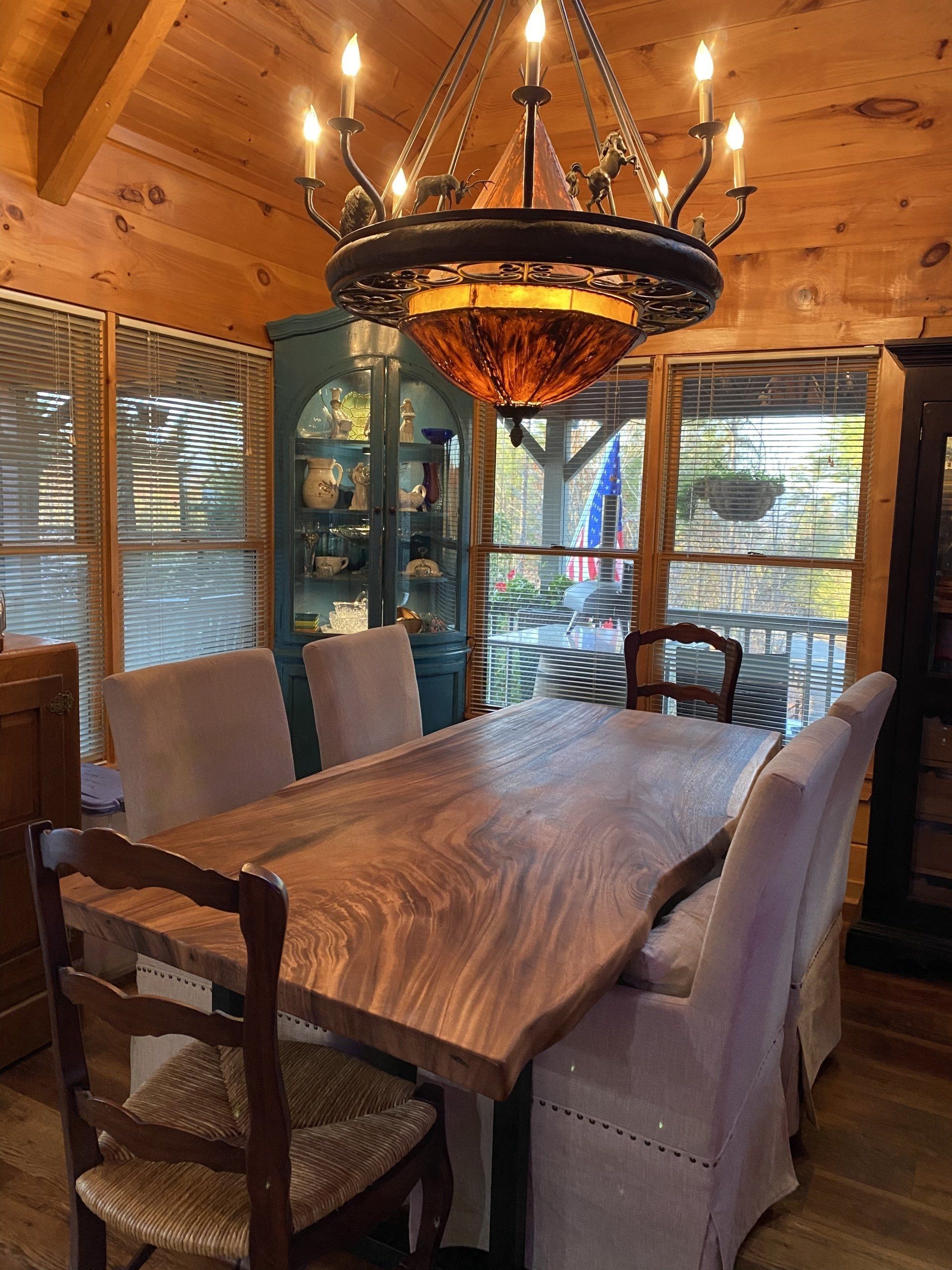 A dining room with a wooden table and chairs and a chandelier hanging from the ceiling.