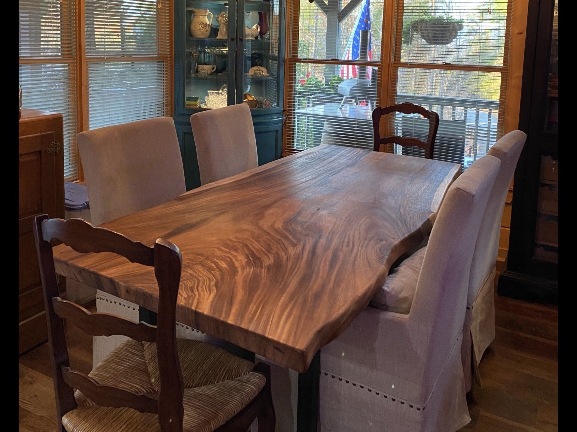 A wooden dining table with chairs in a room with a large window.