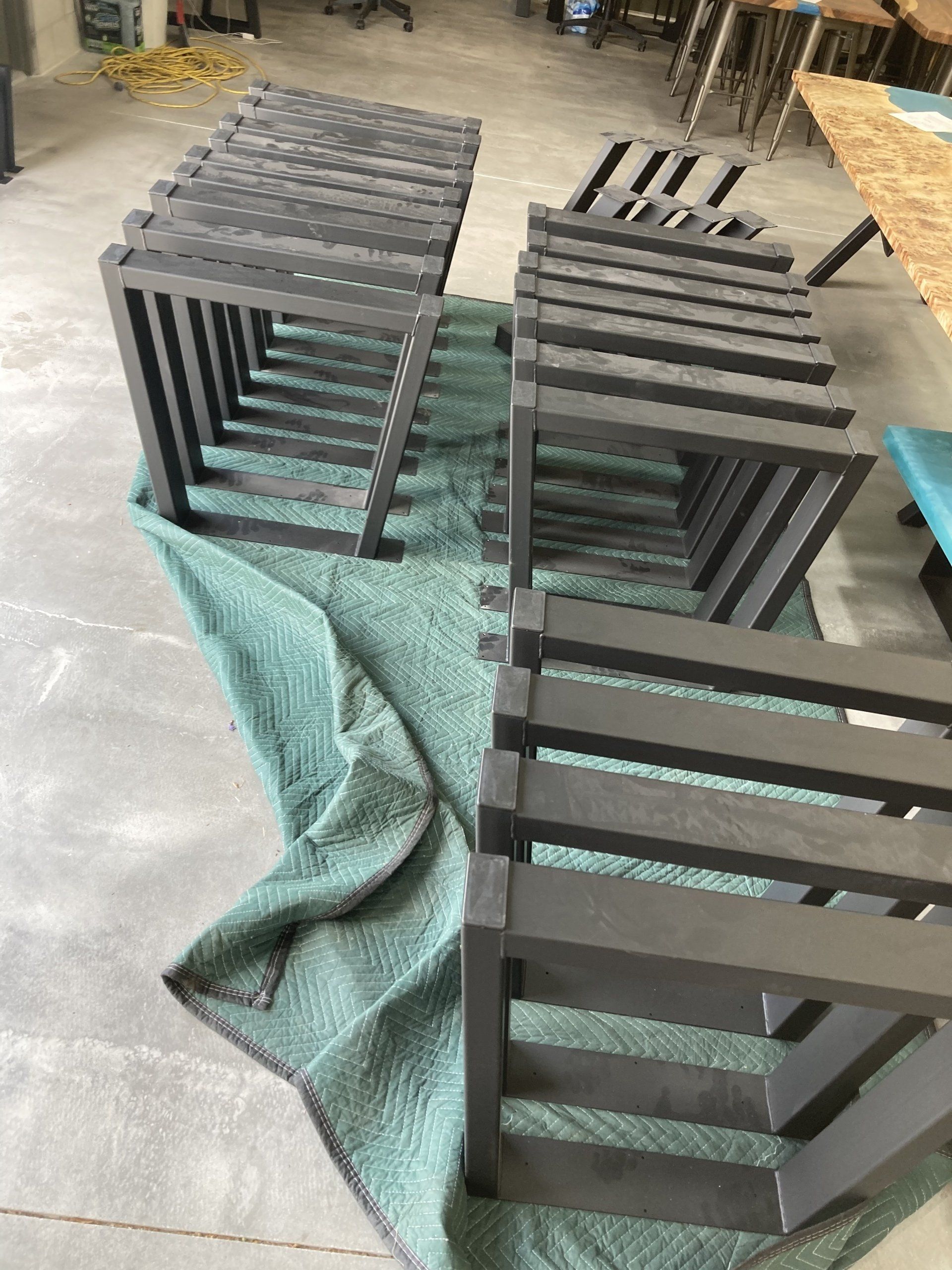 A row of wooden stools are sitting on top of a green blanket.