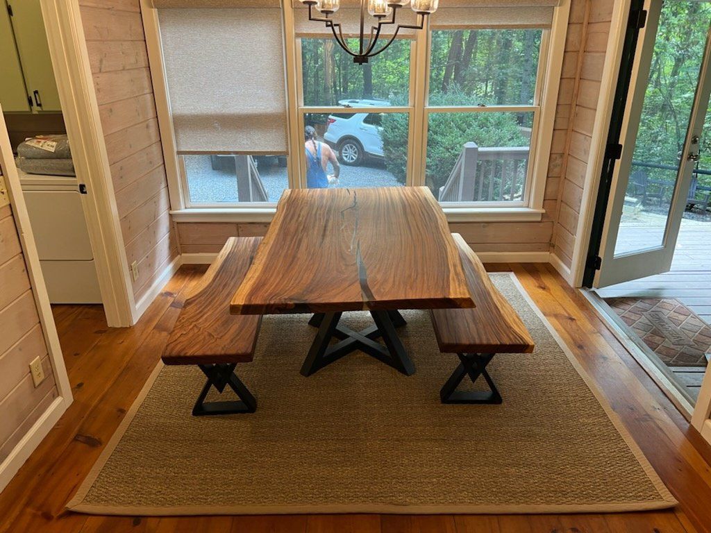A wooden table with two benches in a dining room next to a window.