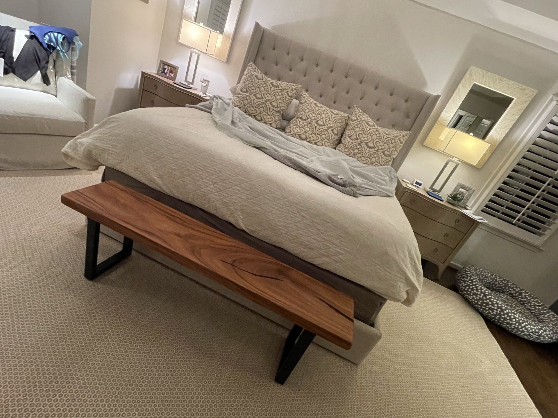 A bedroom with a large bed and a wooden bench.