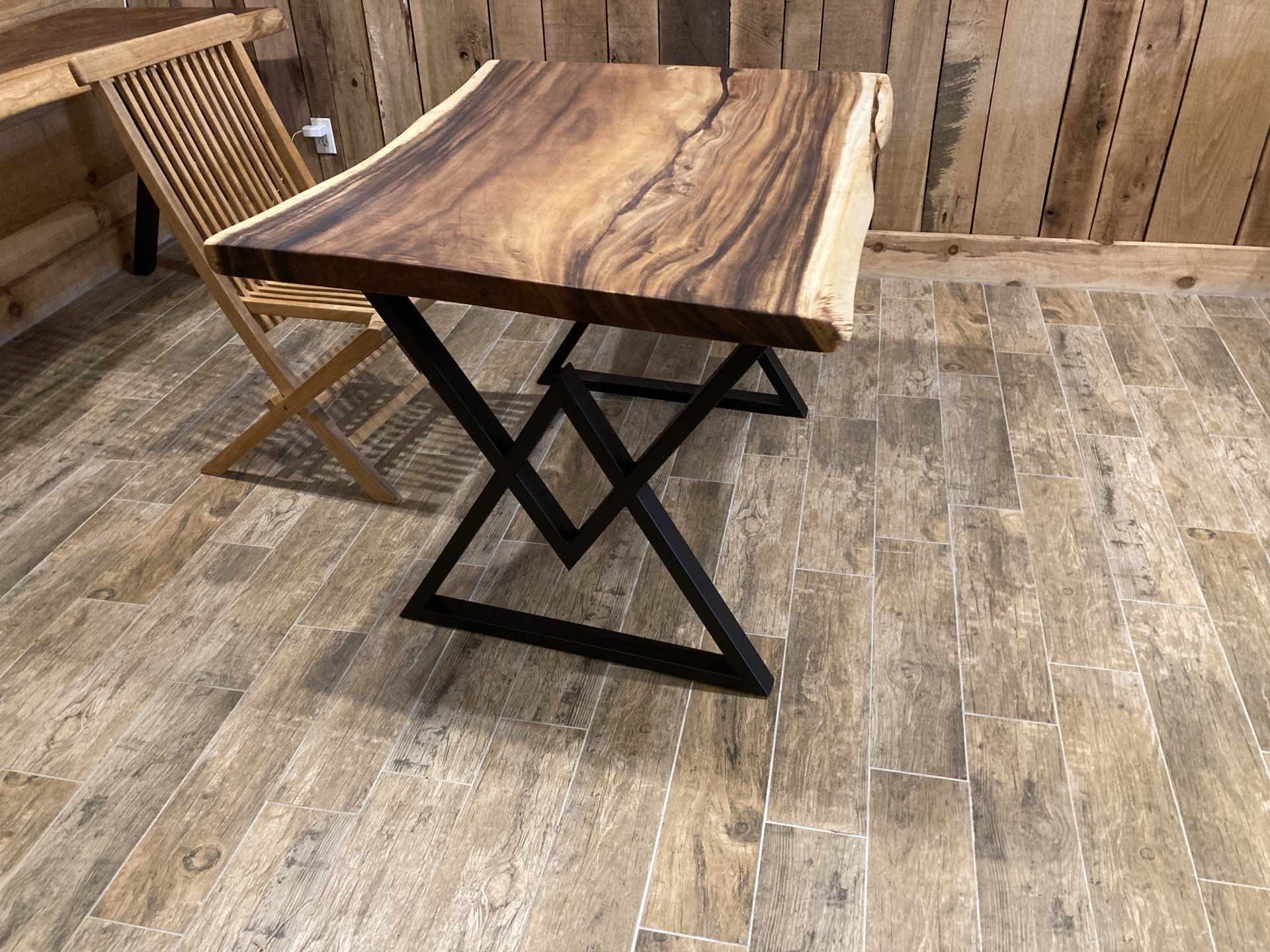 A wooden table with a metal frame is sitting on a tiled floor next to a wooden chair.