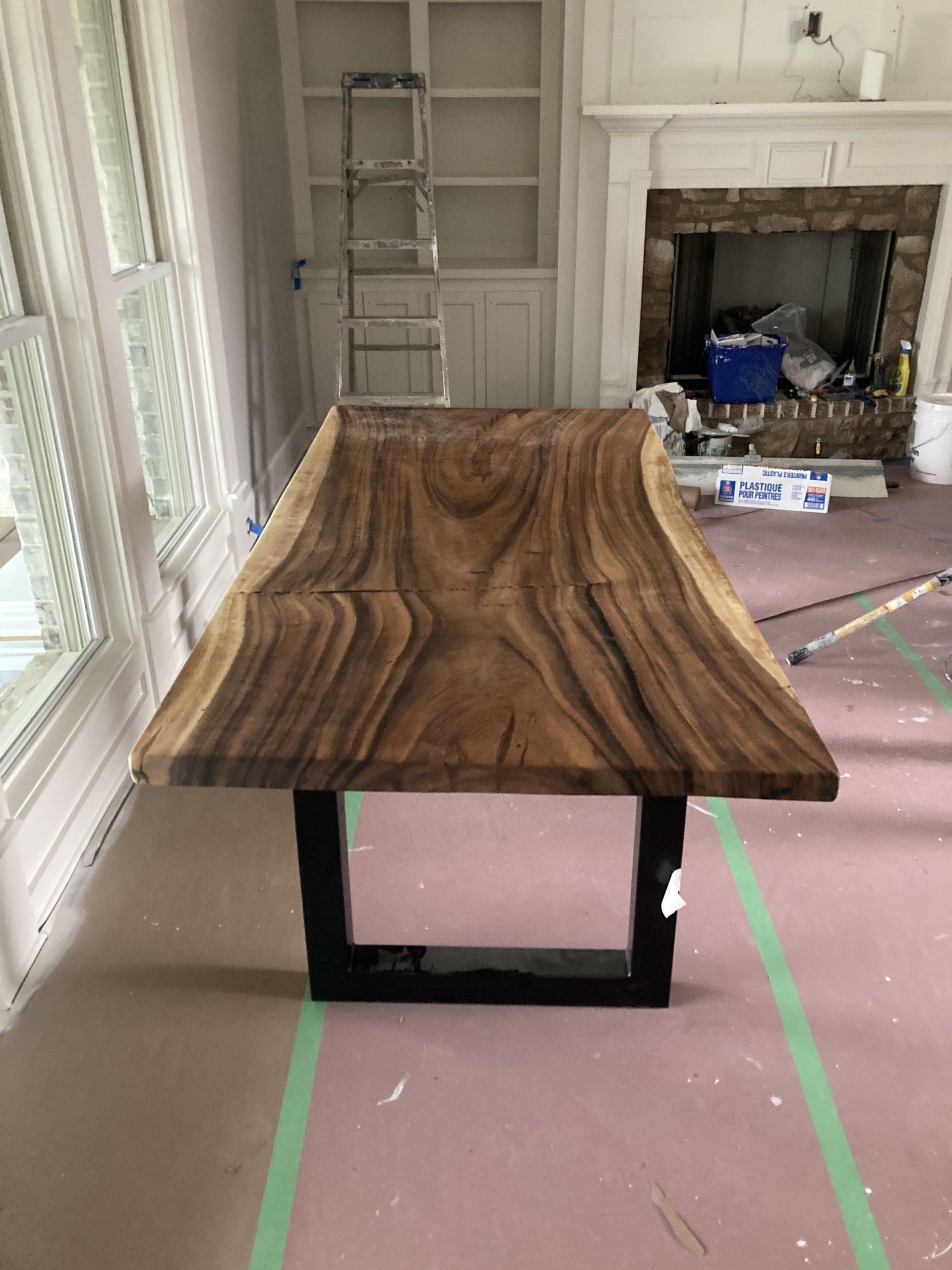 A wooden table is sitting in a living room next to a fireplace.
