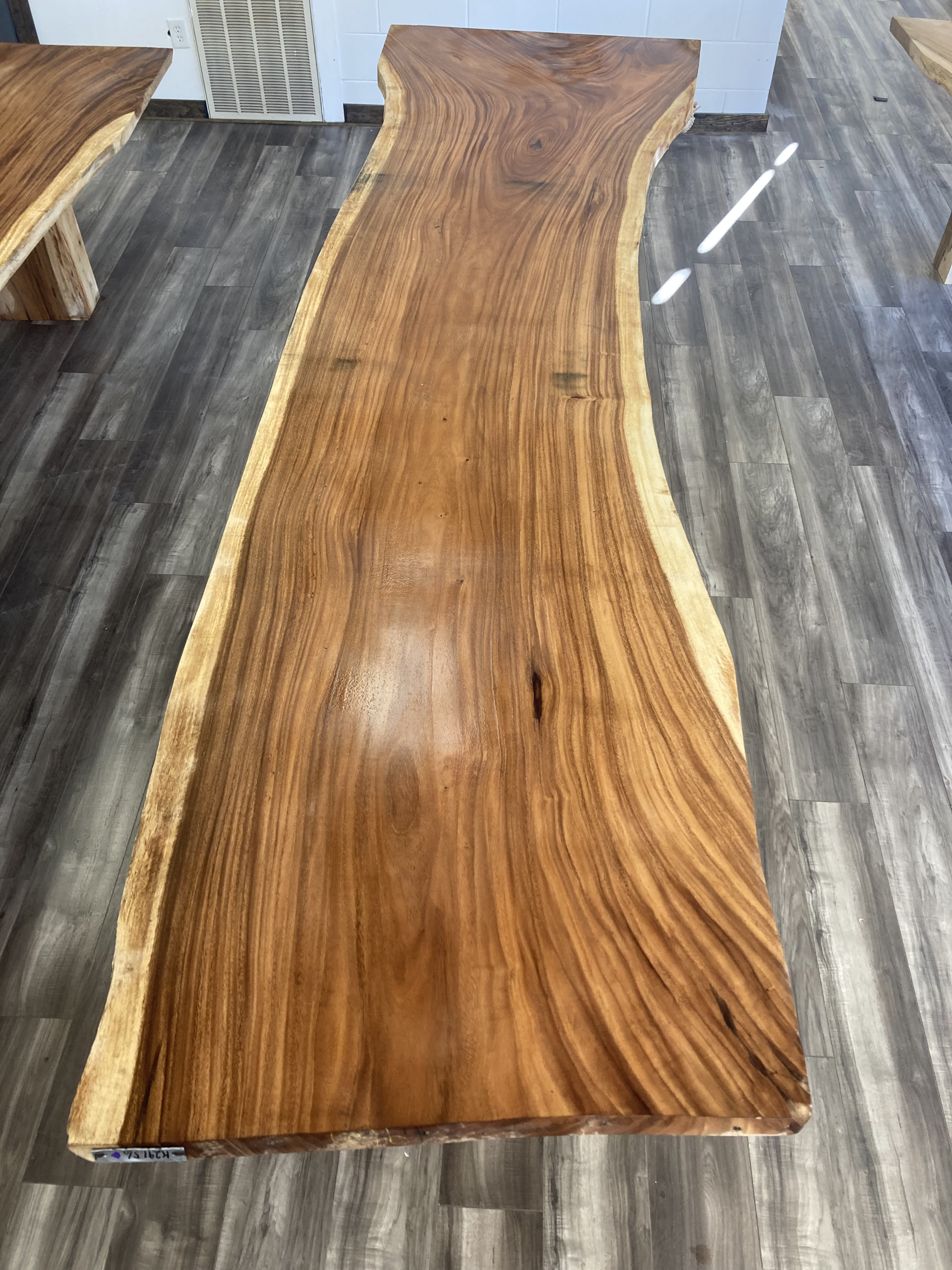 A long wooden table is sitting on a wooden floor in a room.