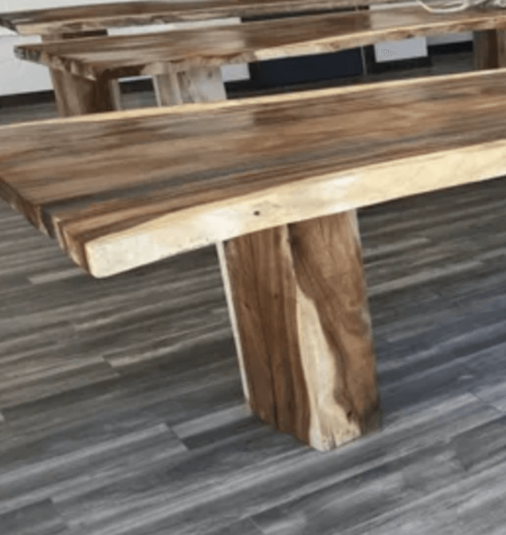 A wooden bench is sitting on a wooden floor next to a wooden table.