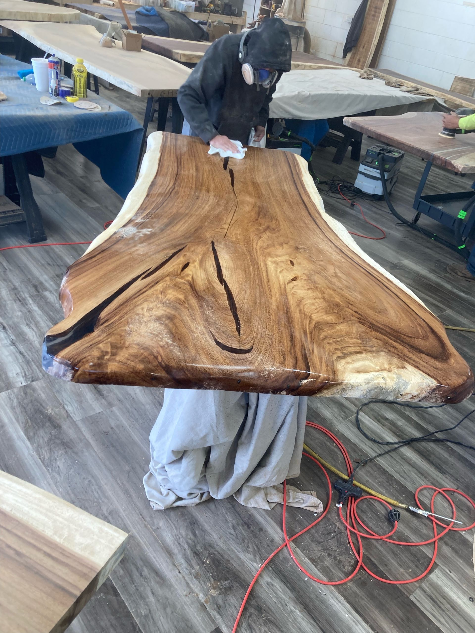 A man is polishing a piece of wood in a workshop.
