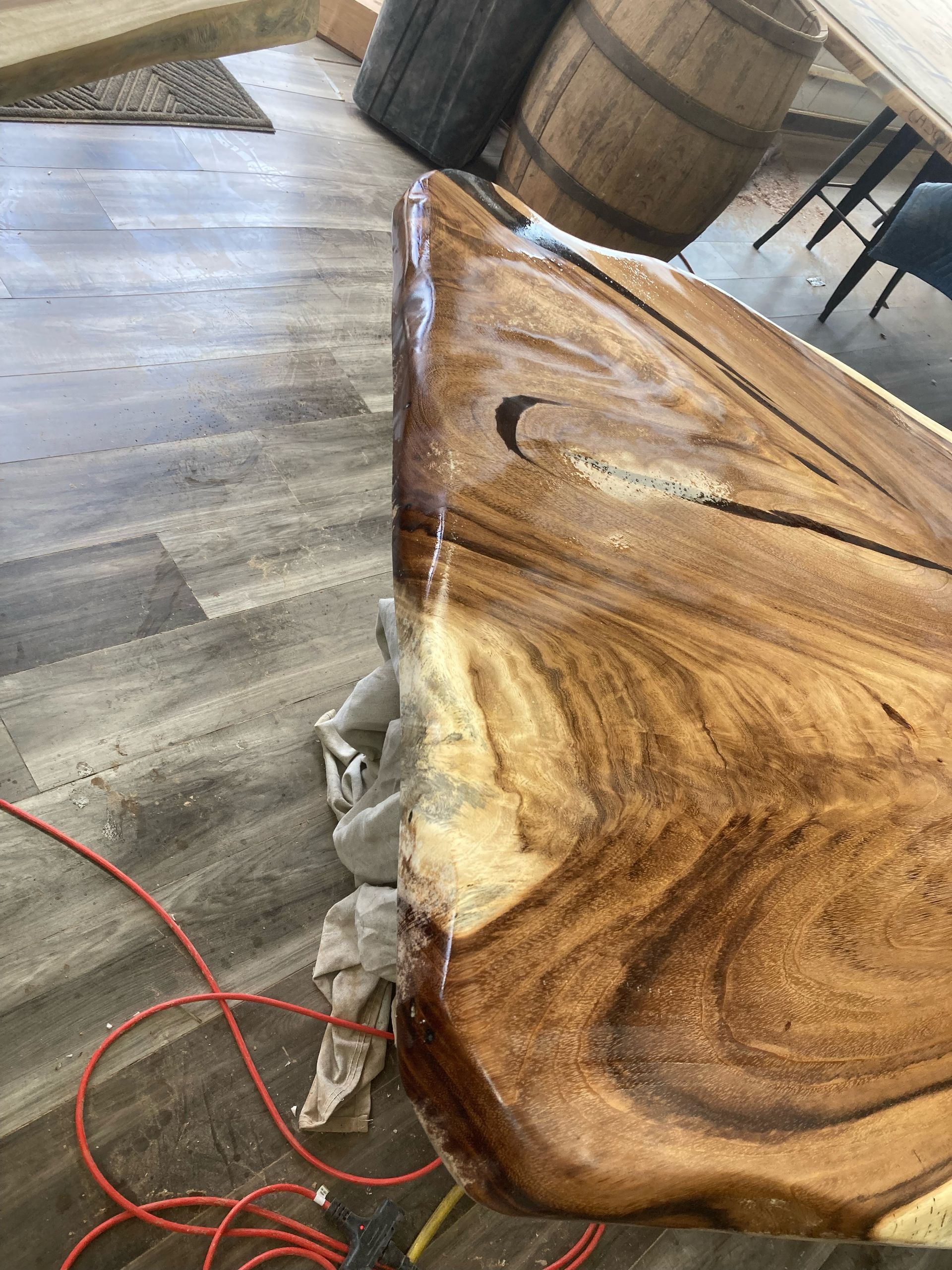A piece of wood is sitting on a wooden floor next to a power cord.