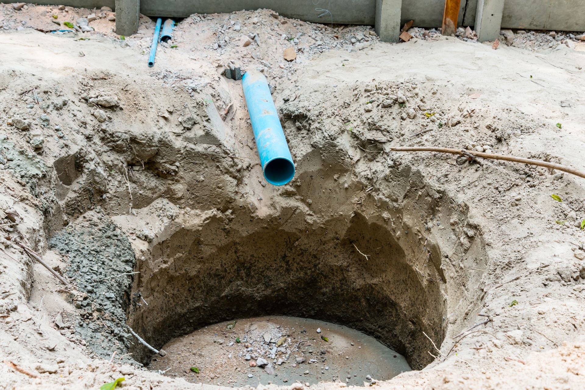 Preparing ground trench for septic system maintenance near bathroom of small residential home.