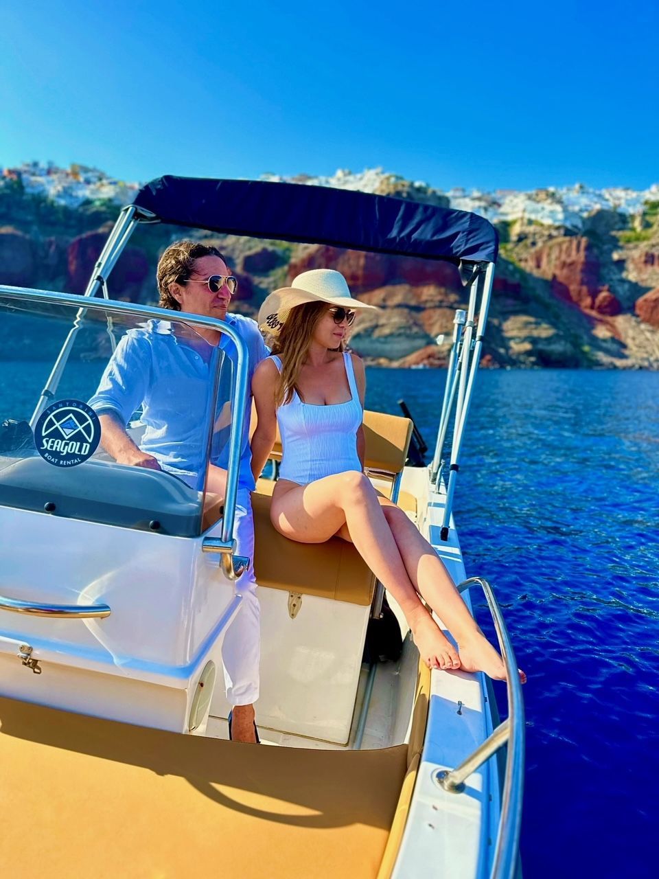 A man and a woman are sitting on a boat in Santorini 