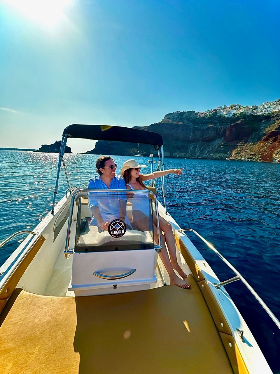 A man and a woman are sitting on a boat in Santorini, Greece 