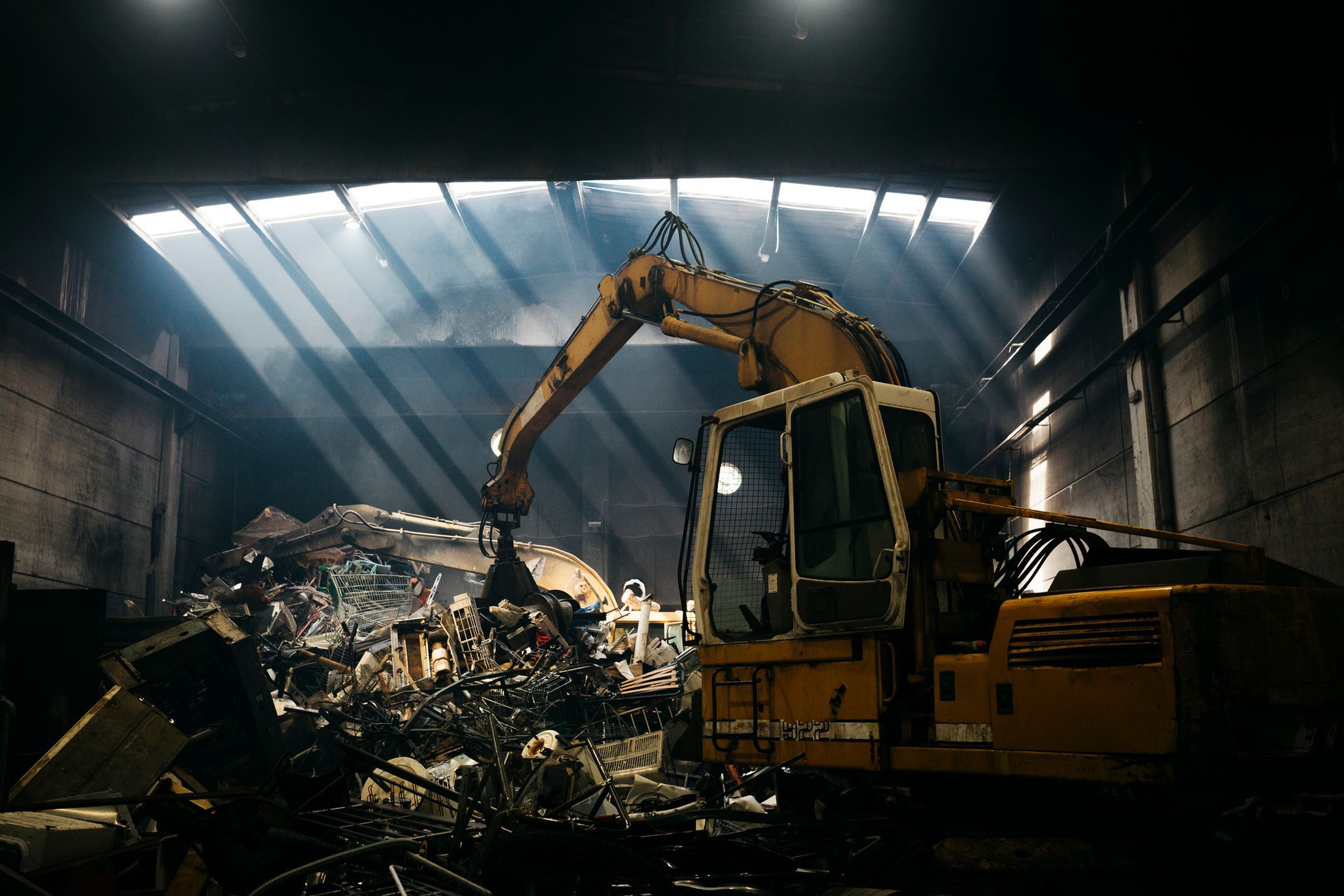 A hydraulic mechanical grabber illuminated with a ray of light in a scrap metal yard A hydraulic mechanical grabber illuminated with a ray of light in a scrap metal yard