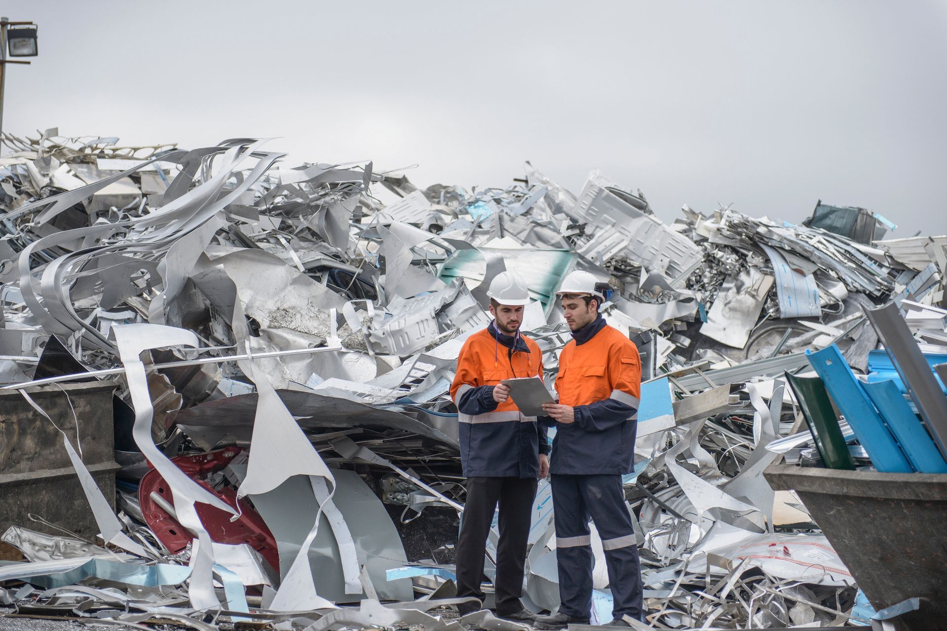 Workers carefully inspecting aluminum scrap at a busy recycling facility.