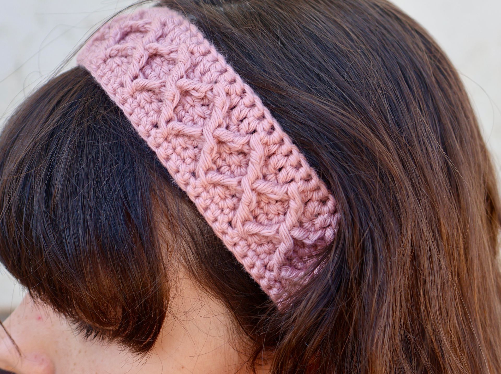 Close-up of a handmade white crochet cotton headband with a textured stitch pattern.