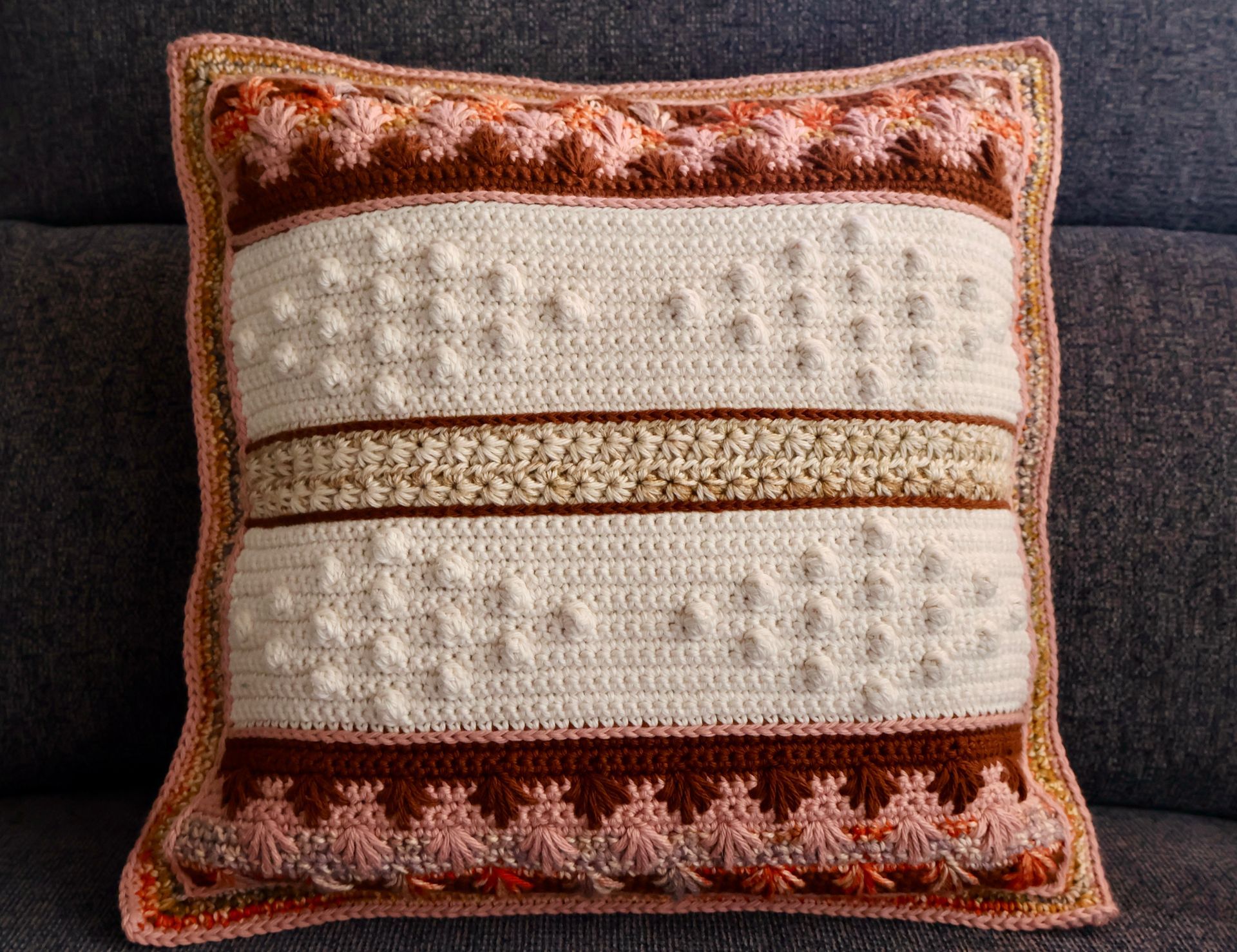 Handmade crochet throw pillow featuring textured bobble stitches, star stitches, and spike stitch