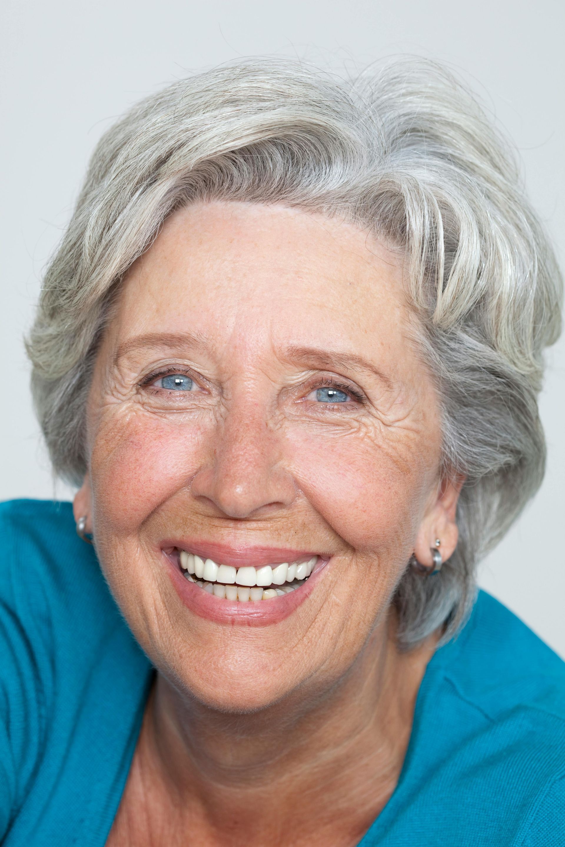 Smiling woman with short gray hair and blue shirt.