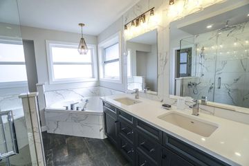A bathroom with two sinks , a tub and two mirrors.