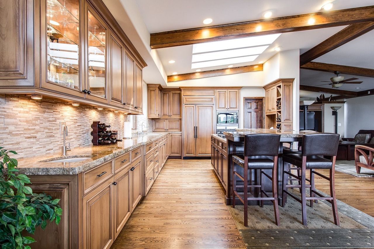 A kitchen with wooden cabinets , granite counter tops , and stools.