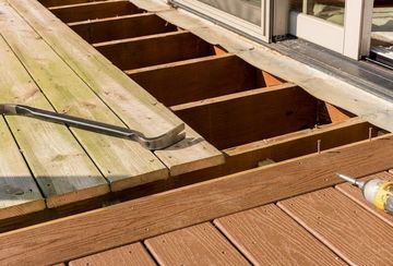 A wooden deck is being built with a hammer and nails.