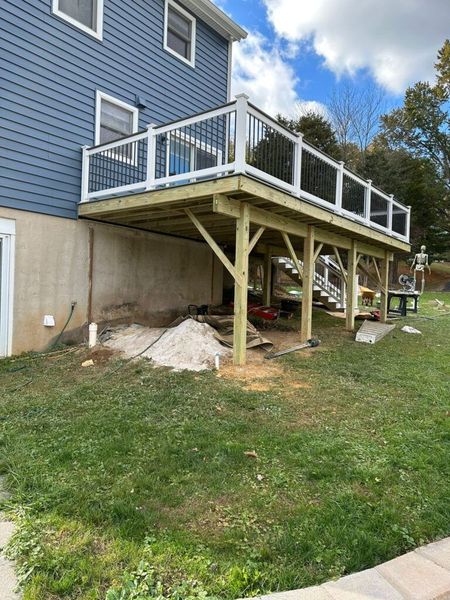 A large wooden deck is being built in front of a blue house.