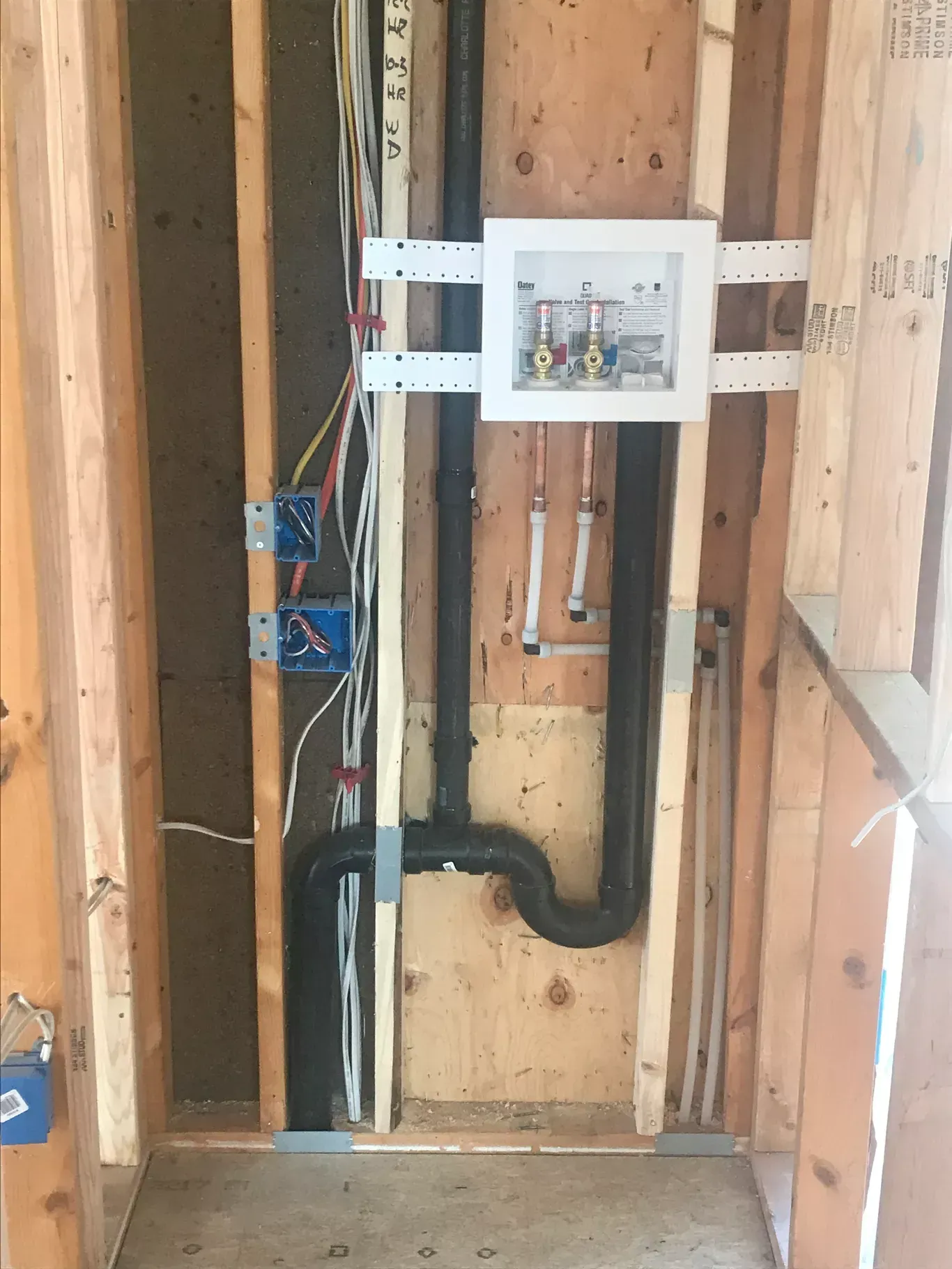A picture of a bathroom under construction with pipes and wires.