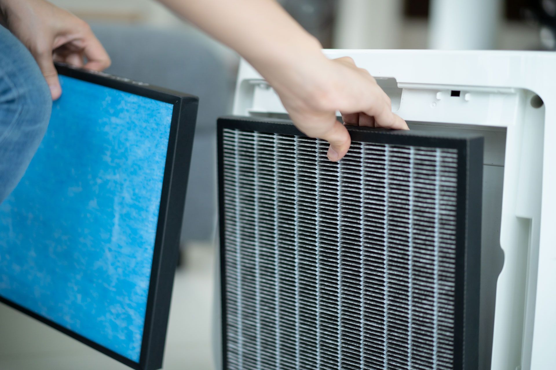 A person is changing a filter on an air purifier.