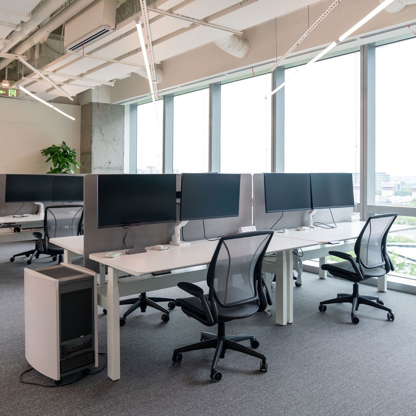 An office with a lot of windows and desks and chairs.